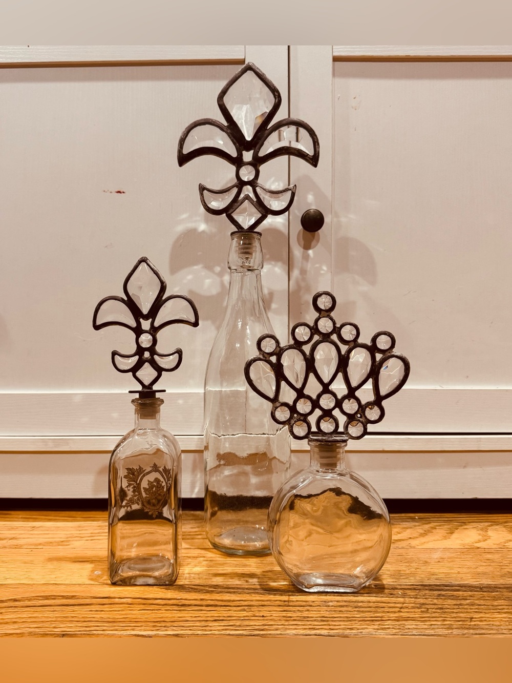 Vintage Decorative Glass Bottle Trio with Fleur & Crown Stoppers - Clear
